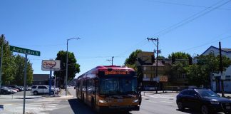 An E Line bus heads northbound on Aurora Avenue N near Green Lake on a sunny day.