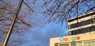 Google's logo is illuminated in the sun at the Kirkland Urban building in Downtown Kirkland. A row of townhouses sits behind.