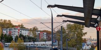 A train pulls into Mount Baker station with the downtown Seattle skyline in the distance.