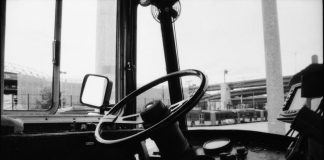 An empty driver seat in a Metro bus with a highway overpass in the background
