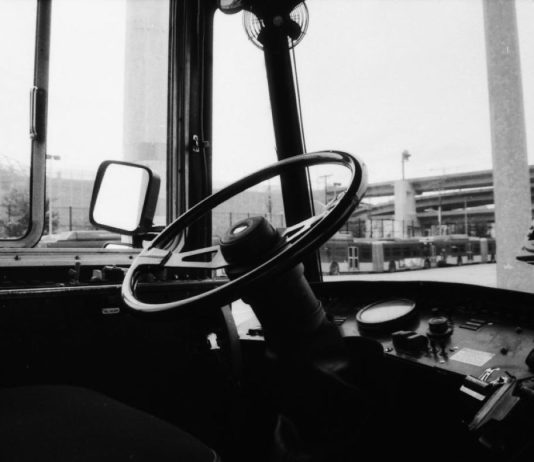 The View From Nathan’s Bus: Shawn Yim and Keeping Transit Safe An empty driver seat in a Metro bus with a highway overpass in the background