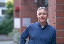 Rory O’Sullivan Launches Progressive Challenge Against Seattle City Attorney Ann Davison A middle-aged man stands outside a brick building