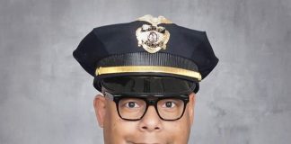 Barnes is a black man with glasses pictured posing in a police uniform.