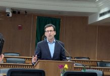 Ferguson Pushes Budget Cuts as Washington Legislature Seeks New Revenue Ferguson stands at the lectern wearing a navy suit and glasses in a Capitol board room.