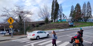 Two people crossing the ramp with one car already having disregarded them. One person is in a wheelchair.