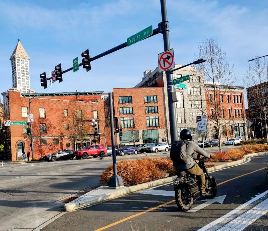 Seattle Releases Road Map for Transportation Levy Spending in 2025 and Beyond Someone on a bike using the new waterfront bike lane with a brightly lit city in the background
