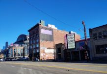 Seattle Council Sharply Divided Over Allowing Housing in Stadium District A photo from SoDo, with T-Mobile Park in the background. An older brick building stands next to smaller, more run down storefronts with a large wide road in the foreground