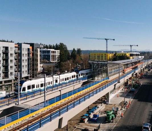 Downtown Redmond Light Rail Opening Set for May 10 A train in testing arriving at Downtown Redmond, with buildings under construction behnind