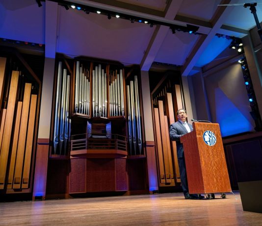 Harrell Teases Plans for Pedestrianizing Pike Place and Overhauling Aurora Avenue Harrell stands at a lectern with a big pipe organ behind him on the Benaroya auditorium stage.