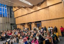 Housing Advocates Outnumber ‘One Seattle’ Opponents, Moore and Rivera Back Opponents The Seattle council chambers are filled to the brim. People hold signs to promote their views.