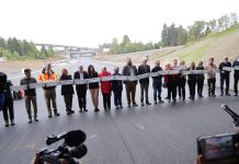 Legislature Considers Cutting Highway Expansion Projects to Address Budget Woes A long line of legislators and other leaders standing on a new segment of SR 509 before a ribbon is cut