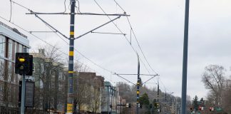 Light rail tracks run down the median of MLK Way in Columbia City station with new four story buildings on either side.