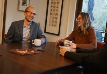 Eddie Lin Pushes Housing in Council Bid to Represent Southeast Seattle Lin is an Asian man with glasses and a suitcoat. He holds a coffee cup and sits next two people, one of them his wife.