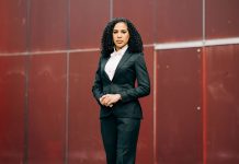 Prosecutor Erika Evans Stresses Federal Experience in Seattle City Attorney Bid Evans is a light-skinned Black woman with curly hair standing in front of a red wall.