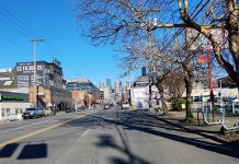 Seattle Council Lifts Ban on Housing in Stadium District The view of wide, but empty First Avenue looking north toward Downtown, with low-slung industrial, strip mall, and parking lots around it.