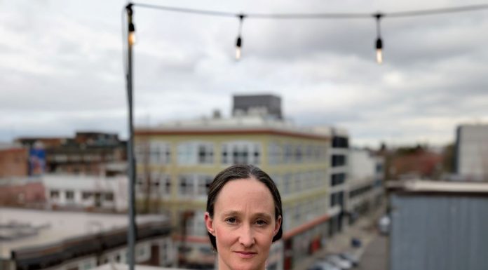Katie Wilson Takes 91-Vote Lead in Dramatic Seattle Mayor Race Wilson stands on a rooftop in Capitol Hill with a Mona Lisa smile. She's a White middle-aged woman with dark hair.