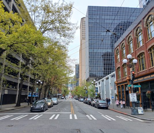 Op-Ed: It’s Time to Bring Transit Back to Seattle’s First Avenue A view north up First Avenue shows a hodge of Pioneer Square historic brick buidlings, tall glass scrapers and a large parking garage.