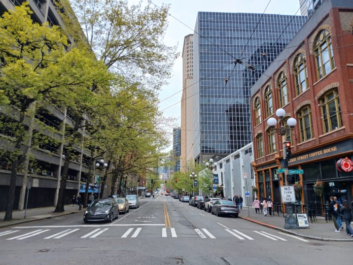 A view north up First Avenue shows a hodge of Pioneer Square historic brick buidlings, tall glass scrapers and a large parking garage.