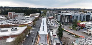 A elevated platform sits on the side of an urban road with a smattering of large midrise apartment buildings bordering it.