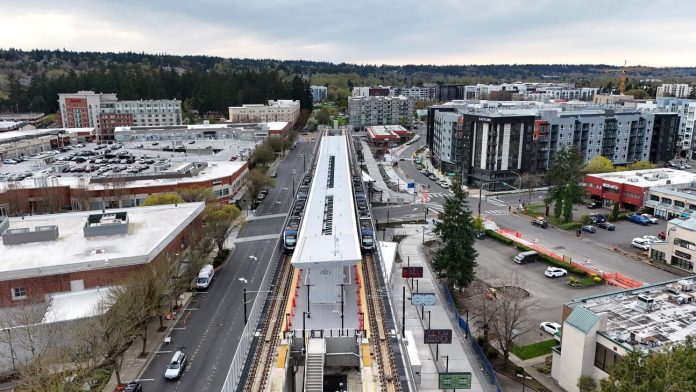 A elevated platform sits on the side of an urban road with a smattering of large midrise apartment buildings bordering it.