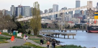 Orange signs warn of the bike path closure just east of Expedia Park. A dozen joggers and dog walkers crowd the waterfront path. The Seattle skyline is in the distance.