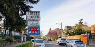 A concrete planter narrow the crossing distance at an intersection with a sign saying "Street closed, local access only, Stay Healthy Street."
