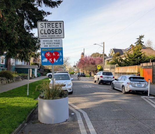 State Bill Could Unleash Potential of Streets, Making Space for People A concrete planter narrow the crossing distance at an intersection with a sign saying "Street closed, local access only, Stay Healthy Street."