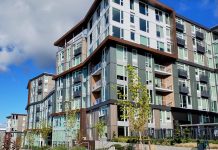 State Senate Greenlights Sweeping Transit-Oriented Housing Bill A large midrise building with some landscaping on the edges and blue skies and a fluffy cloud overhead.