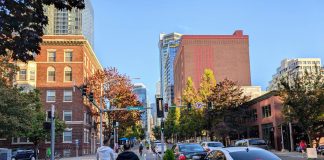 Two riders push off to accelerate on their Lime scooters on the Second Avenue protected bike lane in Belltown.