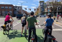 Op-Ed: Anti-Speeding Technology Could Have Saved My Son Five people on bike wait in a green bike lane at a major intersection with car whizzing by and pedestrians waiting on the corner.