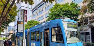 Fare Hike Proposal Would Increase Seattle Streetcar Rides to $3 A blue streetcar at a stop along Westlake Avenue with three passengers on the platform.