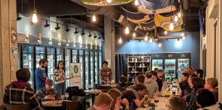 Attendees fill seats in long tables at Teku Tavern two members of House Our Neighbors present to the group.