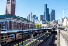 Washington Legislature Greenlights Framework for Amtrak Improvements King Street Station with the downtown Seattle skyline in the background on a clear sunny day.