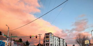 A five-story apartment building along Aurora Avenue with the sunset in the background.