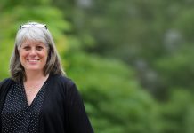 Balducci Claims County Executive Race Lead, John Wilson Mired in Scandal Balducci has her glasses up on her head and smiles. She stands in front of a forest.