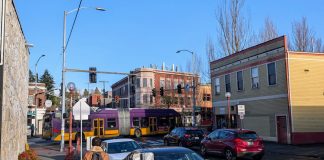 A bus on Rainier Avenue passes by as a pedestrian walks up the side street in Columbia City.