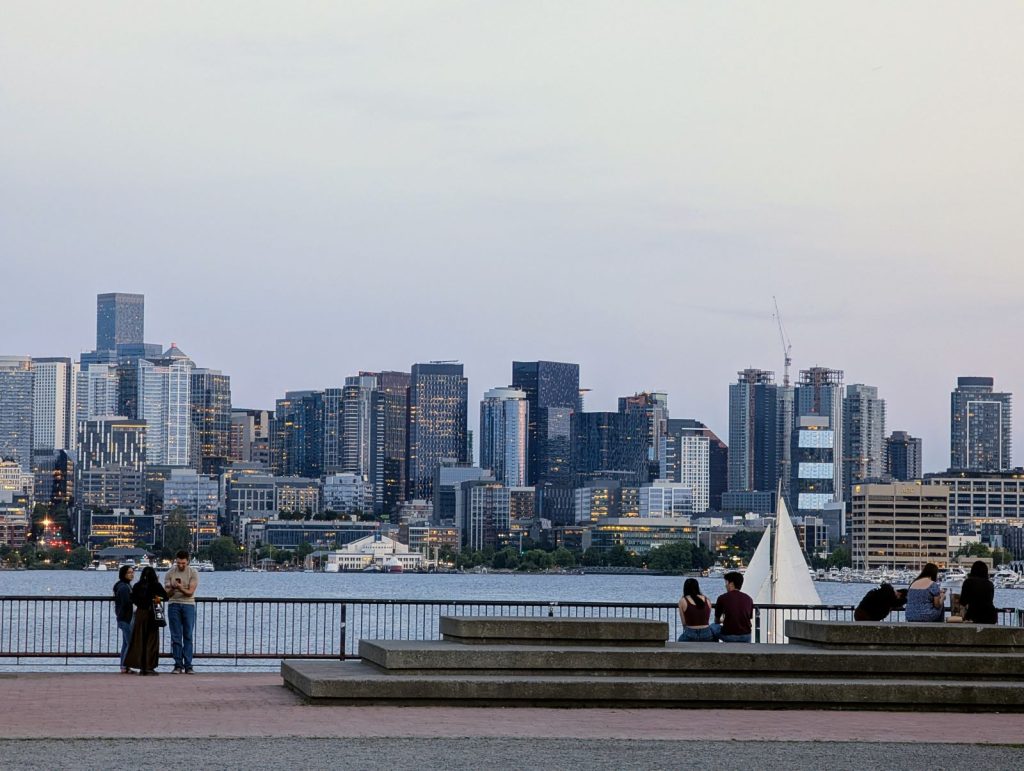 A sailboat passes in front of the seating area at Gas Works with the skyline in the distance