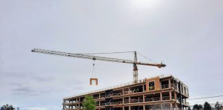 Harrell Proposes Design Review Moratorium, Interim Legislation Complying with State Mandate The mass timber framework is visible on a six-story office building as a tower crane lowers a siding panel into place.