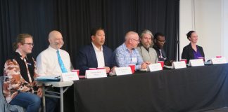 The candidates sit at table with name tags in front.