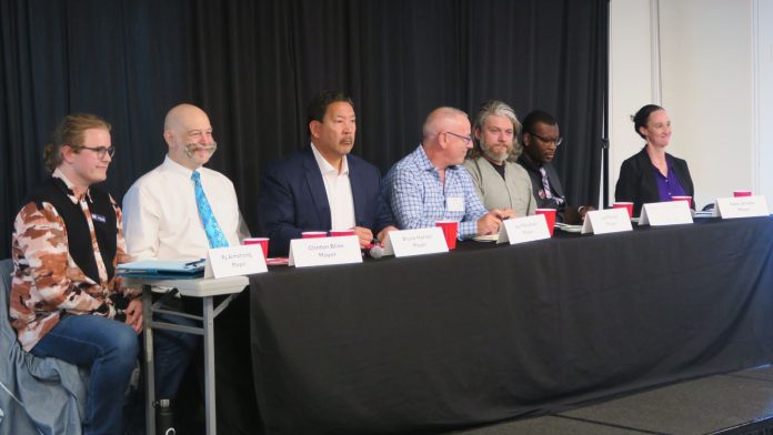 The candidates sit at table with name tags in front.