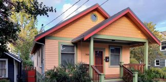 A peach-colored house with teal trim and a grassy lawn