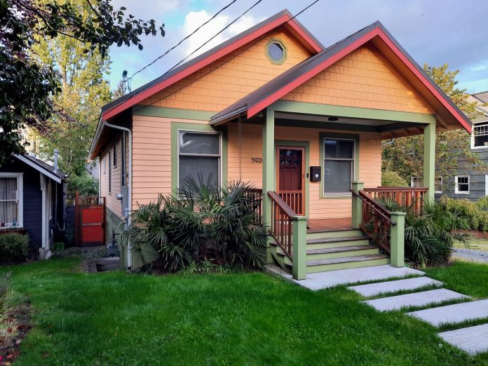 A peach-colored house with teal trim and a grassy lawn
