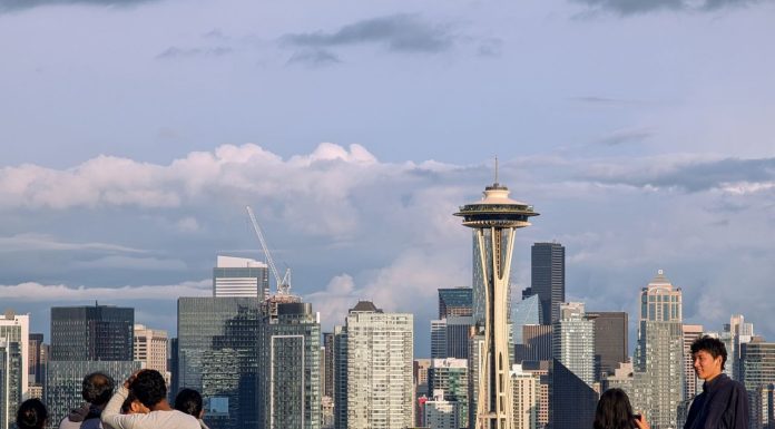 Seattle’s No-Cost Climate Pollution Cut A group of young people stand by the railing at Kerry Point with the Space Needle and downtown skyscrapers looming in the distance.