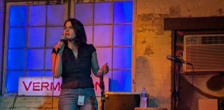 Rinck holds the mic on the Vermillion stage. She has long dark hair and a nose piercing.