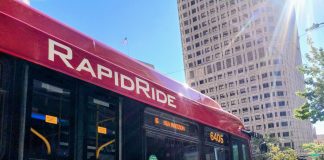 A bright red RapidRide bus with the sun glinting in the sky