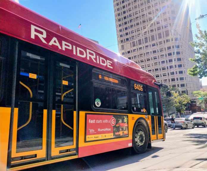 A bright red RapidRide bus with the sun glinting in the sky