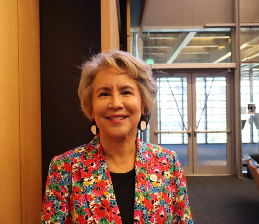 Seattle Council Appoints Debora Juarez to Fill District 5 Vacancy A native woman with grey hair wearing a loud, floral print suit