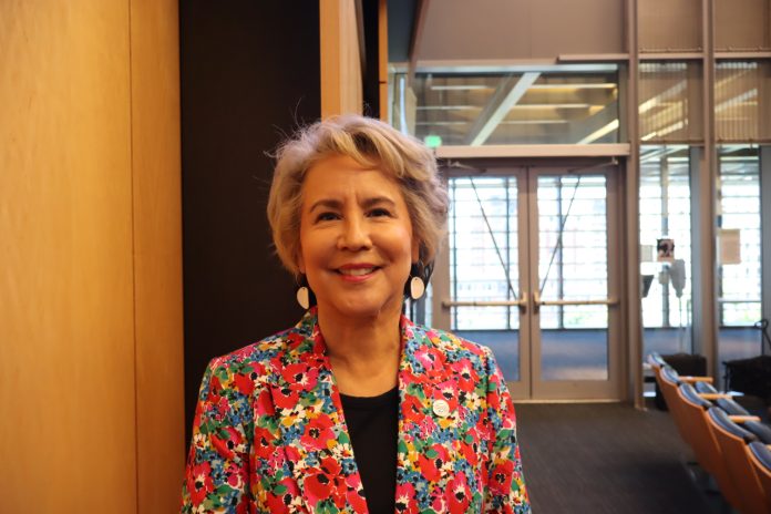 Jaurez A native woman with grey hair wearing a loud, floral print suit
