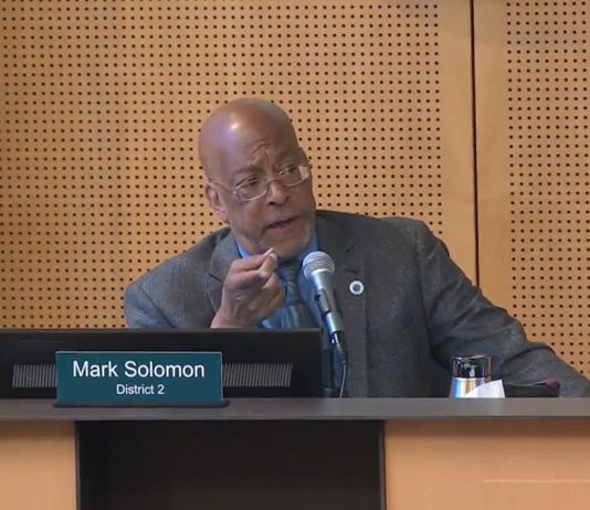 Nelson, Saka Boycott Housing Committee, Blocking Seattle Renters Commission Appointments Solomon is a Black man wears a suit and glasses. He sits at the Council Chambers dais.
