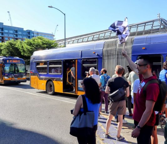 Bus Advocates Race Route 8 to Bolster Case for Improvements A group of pedestrians that raced the Route 8 with two buses in the background.